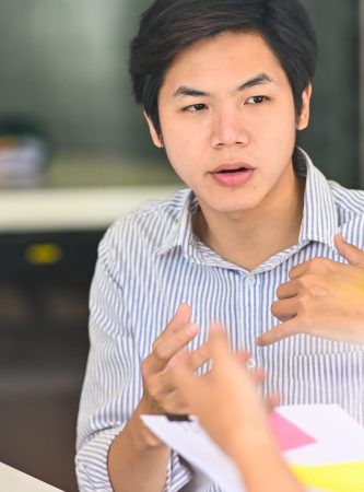Close up young male talking to colleagues consulting in modern office.